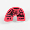 A pink rainbow-shaped lapel pin with black outlines and the words "ME" and "YOU" in black.