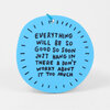 A round blue keychain tag with a small hole at the top and handwritten black text reading, "EVERYTHING WILL BE SO GOOD SO SOON JUST HANG IN THERE & DON'T WORRY ABOUT IT TOO MUCH," surrounded by short black dash marks.