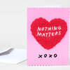 A pink greeting card with scalloped edges features a red heart-shaped chenille patch embroidered with the words "NOTHING MATTERS" and "xoxo" printed below.