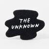 A black chenille patch with the white embroidered text "THE UNKNOWN" in a rounded, irregular shape.