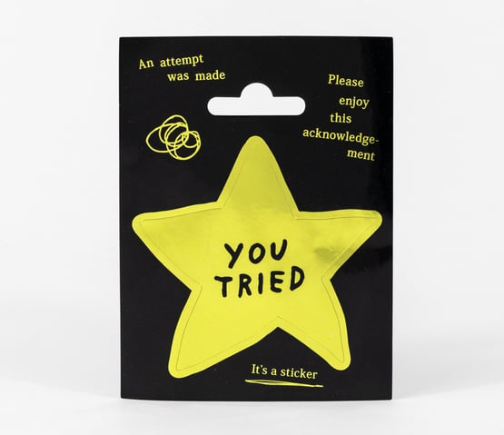 A pale yellow star-shaped sticker on black backing with the words "YOU TRIED" in black, plus small text reading "An attempt was made," "Please enjoy this acknowledgement," and "It's a sticker."