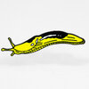 A yellow and black banana slug shaped enamel pin with a long curved body and outlined details.
