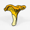 An enamel pin shaped like a yellow chanterelle mushroom with black outlines and pale yellow stem details.