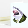 A folded greeting card shows an illustrated great white shark head wearing a green suit jacket, white shirt, and striped tie.