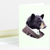 A folded greeting card featuring an illustrated black bear head in a suit, white shirt, green tie, and glasses.