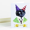 A folded greeting card shows a black cat wearing two striped party hats, a green suit jacket and tie, with a banner reading "HAPPY BIRTHDAY!".