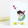 A greeting card shows a narwhal in a green suit and striped party hat with two cupcake candles on its tusk, and a banner that reads "HAPPY BIRTHDAY!"