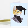 A folded greeting card featuring an illustrated orange cat wearing a black graduation cap and gown on a light blue cover.