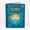 A hardcover journal with a teal floral illustrated cover showing two stylized faces and the title "DREAMER'S JOURNAL" in large gold lettering.