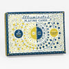 A rectangular box labeled "Illuminated Playing Cards" with ornate blue, yellow, and white decorative artwork, a central sun-and-moon face, and circular callouts reading "2 DECKS FOR GAMES & TAROT" and "INCLUDES INSTRUCTIONAL BOOKLET."