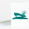 A folded greeting card with a teal illustration of a shoe containing blades of grass above a curved teal ground shape.