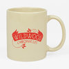 A cream-colored mug with a red "WILDWOOD CHRONICLES" graphic and small leaf flourishes on one side.