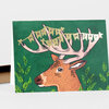 A green greeting card featuring an illustrated deer head with large antlers and a pennant banner that reads "HAPPY BIRTHDAY."