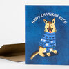 A folded greeting card with a blue cover showing a dog in a patterned blue sweater and the arched text "HAPPY CHANUKAH BITCH".