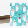A folded greeting card with a teal front pattern of swaddled babies and the word "Congrats!" in cursive script.