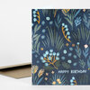A folded greeting card with a dark blue floral and leafy pattern and the words "HAPPY BIRTHDAY" in white on the front.