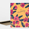 A folded greeting card with an orange cover patterned with pink and navy floral shapes and the text "HAPPY Birthday" in the center.