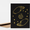 A black greeting card with gold line drawings of two hands and small stars, with the text "I AM HOLDING YOU IN MY HEART" on the front.