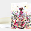 A folded greeting card with a watercolor-style illustration of a smiling child with arms raised, wearing a floral crown and standing amid colorful leafy branches.