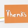 An orange folded notecard with the word "thanks" spelled in white illustrated letters formed by small figures.