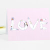 A folded pink greeting card with the word "LOVE" spelled in large illustrated letters made from four figures in white clothing.