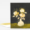 A folded greeting card with an abstract floral painting of three cream and yellow flowers on a dark background, with a white envelope partially visible behind it.