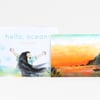 A children’s book cover titled "hello, ocean!" by Corinna Luyken with an illustrated child raising both arms above a pastel ocean scene, plus a second cover image showing a warm orange sunset over the water and coastline.