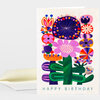 A folded greeting card with a colorful stylized flower garden illustration and the words "HAPPY BIRTHDAY" printed at the bottom.