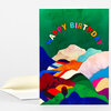 A folded greeting card with a colorful abstract landscape design and the arched text "HAPPY BIRTHDAY" on the front, shown with a plain envelope.
