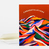A folded greeting card with the word "CONGRATULATIONS" on the front above a colorful abstract mountain-like pattern.