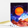 A folded birthday greeting card with a starry purple sky, a large orange moon, and colorful striped mountain shapes, with the text "HAPPY BIRTHDAY" across the top.