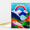 A vertical greeting card with a colorful rainbow arch over layered stylized mountains in blue, pink, green, orange, and striped patterns, with a matching white envelope behind it.