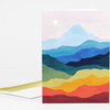 A folded greeting card featuring a stylized landscape of layered mountains in blue, green, yellow, orange, and red with a small white sun near the top.