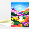 A folded greeting card with a colorful abstract rolling hills illustration and the words "HAPPY BIRTHDAY" arched across the top.