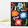 A folded greeting card with a black front covered in colorful stylized flowers and vines, including blue, orange, red, and pink blooms.