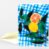 A folded greeting card with a blue checkered pattern, green leaves, an orange slice, and a yellow citrus fruit illustration on the front.