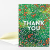 A folded greeting card with a green wildflower meadow illustration and large white text reading "THANK YOU" on the front.