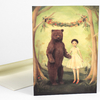 A greeting card shows an illustrated bear standing beside a girl in a white dress under a floral garland.