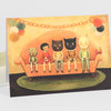 A greeting card shows five children in animal costumes sitting on an orange sofa, with balloon garlands and a small red radio on the armrest.