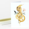 A folded greeting card with a watercolor illustration of a yellow serpent wrapped around stems and pink flowers.