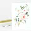 A folded greeting card with a watercolor illustration of white and pale pink roses with green leaves on the front.