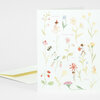 A folded greeting card with a pastel floral illustration and small whimsical figures, with the text "HAPPY BIRTHDAY TO YOU" on the front.