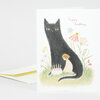 A folded birthday greeting card with a hand-drawn black cat, a small child, flowers, a cake, and the handwritten words “happy birthday.”