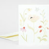 A folded greeting card with a delicate pastel floral illustration, including a large central flower, small blossoms, and red strawberry-like berries on the front.