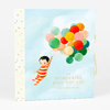 A hardcover baby memory book with a light blue cover, a cream spine with gold stars, an illustration of a child holding a bunch of colorful balloons, and the title text "THE WONDERFUL BABY YOU ARE" with the subtitle "a record of baby's first year".