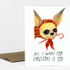 A folded greeting card with an illustrated chihuahua wearing a red plaid hood and candy cane scarf, with the text "ALL I WANT FOR CHRISTMAS IS YOU" on the front.