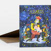 A folded greeting card with the word "AQUARIUS" in yellow at the top and a colorful illustrated figure surrounded by stars and flowers on a dark blue background.