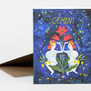 A folded greeting card with a Gemini illustration showing two mirrored figures, a large red flower, stars, and the word "GEMINI" at the top.