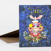 A folded greeting card with the word “LIBRA” in yellow at the top and an illustrated zodiac figure surrounded by stars and flowers on the front.