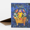 A vertical greeting card with the word "TAURUS" at the top and an illustrated horned figure riding a bull surrounded by stars and flowers.